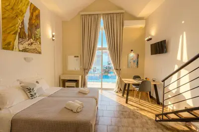 a bedroom with two beds and a table and a balcony at Ilios Mare Hotel in Agia Marina Nea Kydonias