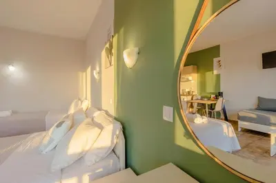 a room with two beds with a mirror and a couch at Ilios Mare Hotel in Agia Marina Nea Kydonias