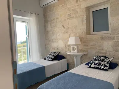two beds in a bedroom with a stone wall at villa Elaionas in Tsivarás