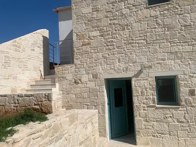 a stone building with a green door and stairs at villa Elaionas in Tsivarás