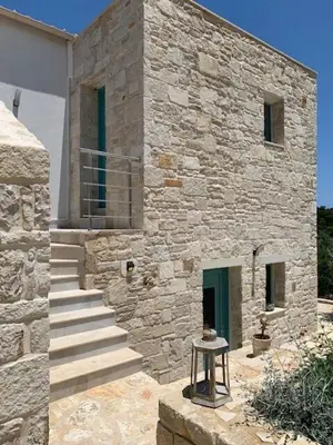 a stone building with stairs leading to a door at villa Elaionas in Tsivarás