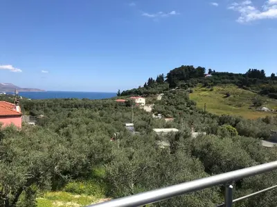 a view of a hill with trees and the ocean at villa Elaionas in Tsivarás