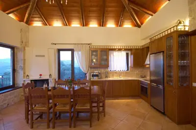 a kitchen with a table and chairs and a kitchen with wooden cabinets at Dream Hill Villas in Tavronitis
