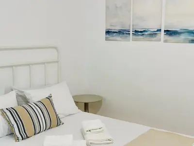 a bedroom with a white bed with two pictures on the wall at Nomas Home, Kalyves Centre Beachfront Sea View in Kalyves