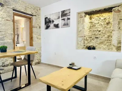 a room with a table and chairs and a stone wall at Nomas Home, Kalyves Centre Beachfront Sea View in Kalyves