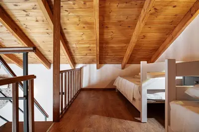 a loft bedroom with wooden ceilings and a staircase at To Petrino Stone Mountain Retreat with Private Pool in Rodhopós