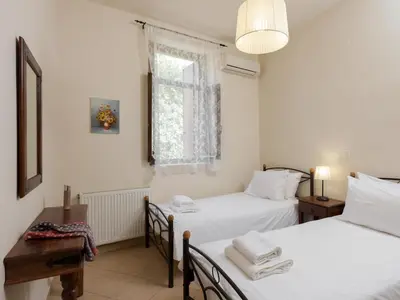 two twin beds in a room with a window at 3-Min Drive to Kalyves Beach, Stone Villa in Armenoi next to Cafés & Taverns by the Natural Water Springs in Arménoi