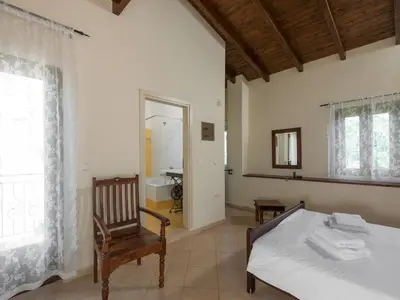 a bedroom with a bed and a chair and a mirror at 3-Min Drive to Kalyves Beach, Stone Villa in Armenoi next to Cafés & Taverns by the Natural Water Springs in Arménoi