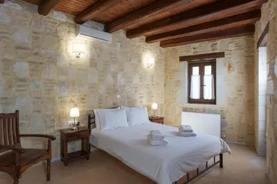 a bedroom with a bed in a stone wall at 3-Min Drive to Kalyves Beach, Stone Home with Private Pool in Armenoi Center in Arménoi