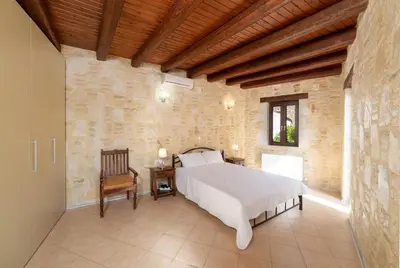 a bedroom with a bed in a stone wall at 3-Min Drive to Kalyves Beach, Stone Home with Private Pool in Armenoi Center in Arménoi