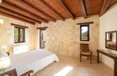 a bedroom with a bed and a wooden ceiling at 3-Min Drive to Kalyves Beach, Stone Home with Private Pool in Armenoi Center in Arménoi