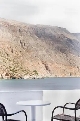 two chairs and a table in front of a lake at Daskalogiannis Hotel in Loutro