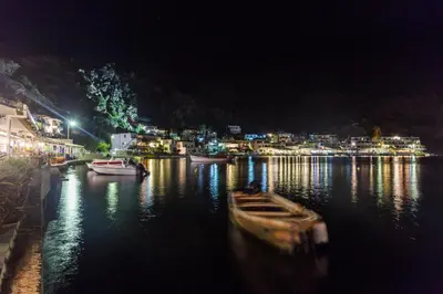 a boat in the water with a city at night at Daskalogiannis Hotel in Loutro