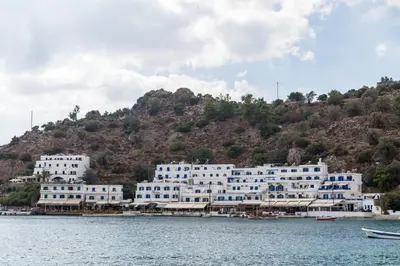 a large white building on a hill next to the water at Daskalogiannis Hotel in Loutro