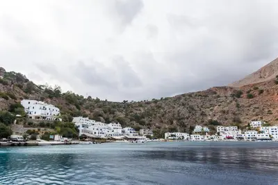a group of white buildings on the shore of a body of water at Daskalogiannis Hotel in Loutro