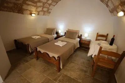 a bedroom with two beds and a table with a bottle of wine at SternesVillage, Middle Ground Floor in Stérnai