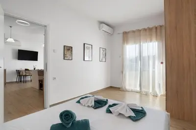 a white room with a bed and a large window at Cozy Apartment Next To The Beach In Almyrida -BY APOKORONAS VILLAS in Almirida