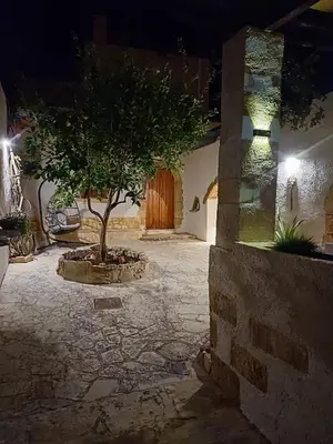 a courtyard with a tree in front of a wooden door at Violetta Kaliviani room 1 in Kalivianí