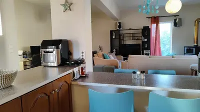 a kitchen with a counter with blue chairs and a living room at John's TownHouse Chania in Tsikalariá