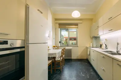 a kitchen with white cabinets and a dining table at Leda's Nea Chora Flat, Near Beach and Old Port in Chania Town