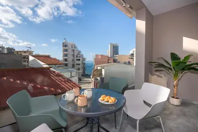 a room with a table and chairs on a balcony at KHORA Apartment- 40m to Sandy Beach in Chania Town