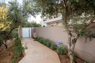 a building with a fence and a tree next to a sidewalk at Mystrali I in Galatás