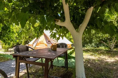 a wooden table under a tree next to a tent at Edem private camping in Análipsis