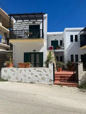 a white house with a fence in front of it at Azure Sea Bliss at The Erodios Apartments in Kalyves