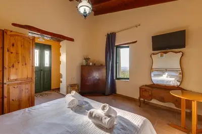 a bedroom with a bed and a tv on the wall at The Yellow Veranda - Close to Ancient Olive Tree of Vouves in Áno Voúvai