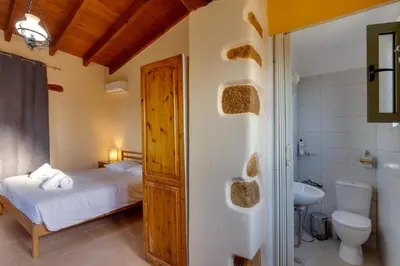 a bedroom with a bed and a toilet and a sink at The Yellow Veranda - Close to Ancient Olive Tree of Vouves in Áno Voúvai
