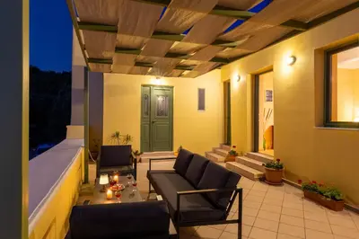 a patio with a couch and chairs and a green door at The Yellow Veranda - Close to Ancient Olive Tree of Vouves in Áno Voúvai