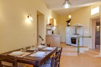 a dining room with a table and a kitchen at The Yellow Veranda - Close to Ancient Olive Tree of Vouves in Áno Voúvai