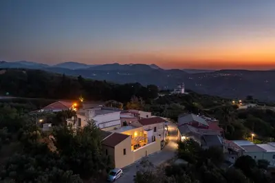 a view of a village at night with the sun setting at The Yellow Veranda - Close to Ancient Olive Tree of Vouves in Áno Voúvai