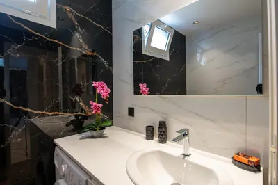 a bathroom with a sink and a mirror and pink flowers at Mystrali II in Galatás