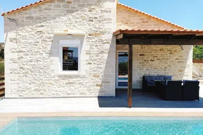 a villa with a pool in front of a building at Villa Naiades Traditional Cretan Stone House with private Pool and Garden in Chania in Arménoi
