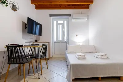 a room with a bed and a table and a tv at Sea & City - Luxury Maisonette Steps from the Beach with Private Terrace in Chania Town