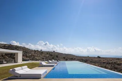 a swimming pool with white lounge chairs next to a mountain at Orus Villa in Chania Town