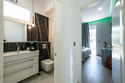 a bathroom with a sink and a toilet and a bed at Adriana Horizon Villa, Pool & Hillside View in Galatás