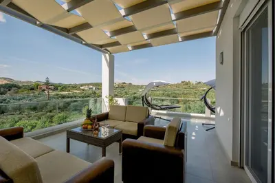 a living room with a couch and chairs and a large window at Adriana Horizon Villa, Pool & Hillside View in Galatás
