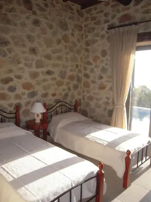 two beds in a room with a stone wall at Villa Santouraki in Keramotí