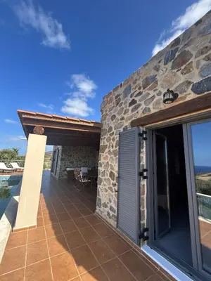 a patio of a stone house with a view of the ocean at Villa Santouraki in Keramotí