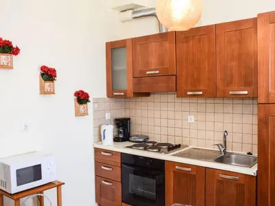 a kitchen with wooden cabinets and a sink and a microwave at Apartment Charmante Ferienwohnung Rubini 2 by Interhome in Agia Marina Nea Kydonias