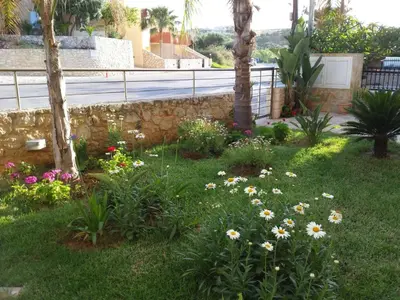 a garden with flowers in the grass next to a fence at Apartment Moderne Wohnung Rubini 3 by Interhome in Chania Town