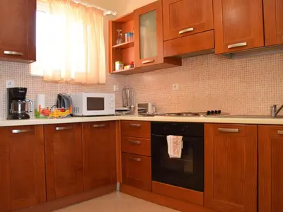 a kitchen with wooden cabinets and a black oven at Apartment Rubini 1 by Interhome in Agia Marina Nea Kydonias