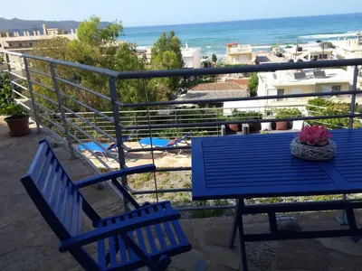 two blue chairs and a table on a balcony with the ocean at Apartment Gemütliche Ferienwohnung Rubini 4 by Interhome in Agia Marina Nea Kydonias