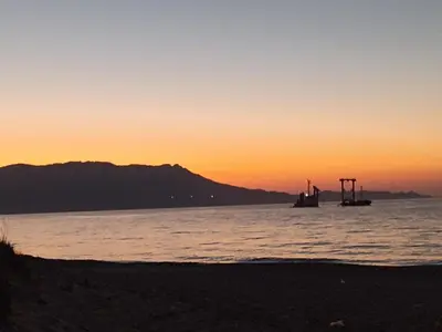 a boat in the water at sunset on the beach at Ifigenias House in Kissamos