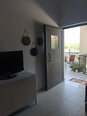 a living room with a television and a door with a porch at Ifigenias House in Kissamos