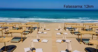a beach with umbrellas and chairs and the ocean at Ifigenias House in Kissamos