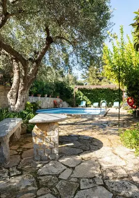 a stone bench in front of a swimming pool at Villa Levedeli in Nerokhórion