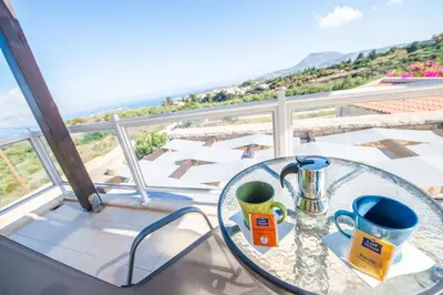 a glass table with two mugs on top of a balcony at Villa Anna Gaia In Tzivaras in Tsivarás